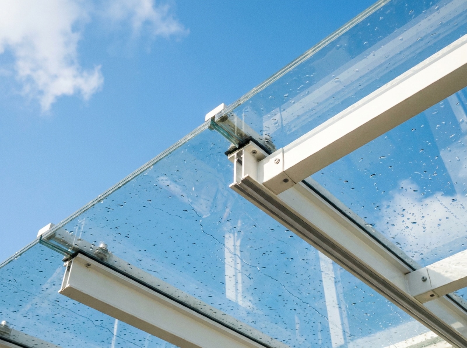 Detailansicht eines Terrassendachs aus Verbundsicherheitsglas mit Regentropfen und schlanken Aluminiumträgern